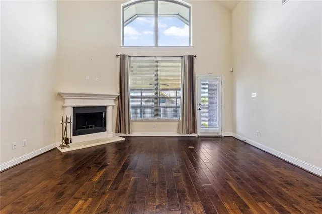 an empty room with wooden floor fireplace and windows