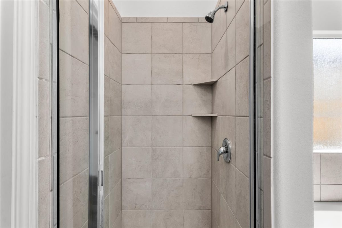 448 Perfect World Loop Jarrell, TX 76537 - Photo 31 of 40 A well-appointed shower with tiled walls and convenient built-in shelving for bath essentials.