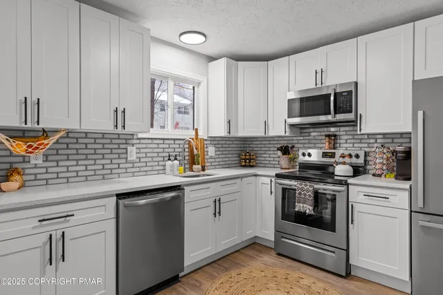 a kitchen with stainless steel appliances granite countertop a sink stove oven and white cabinets