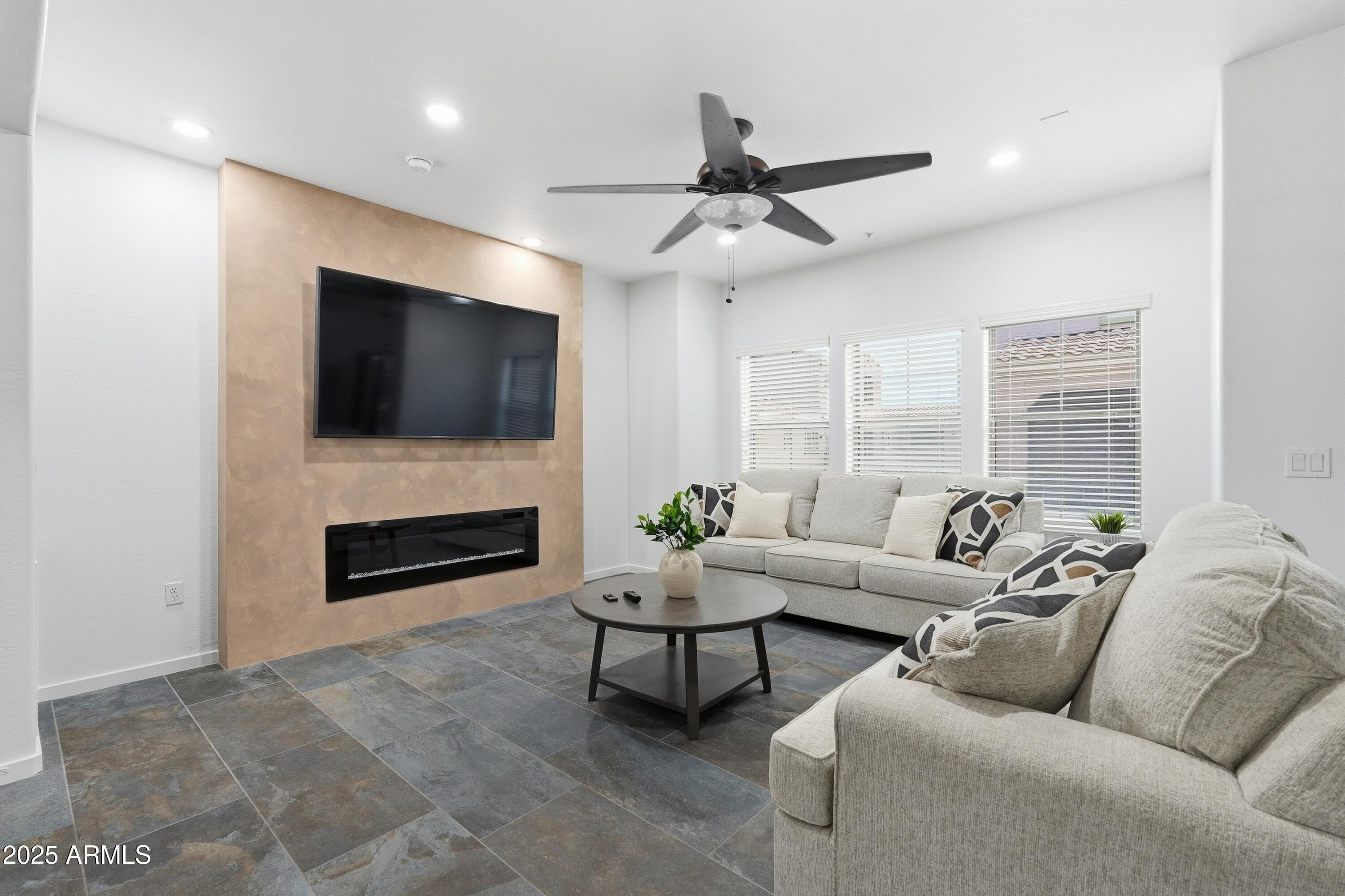 3935 East Rough Rider Road, Unit 1140 Phoenix, AZ 85050 - Photo 2 of 24 a living room with furniture a fireplace and a flat screen tv