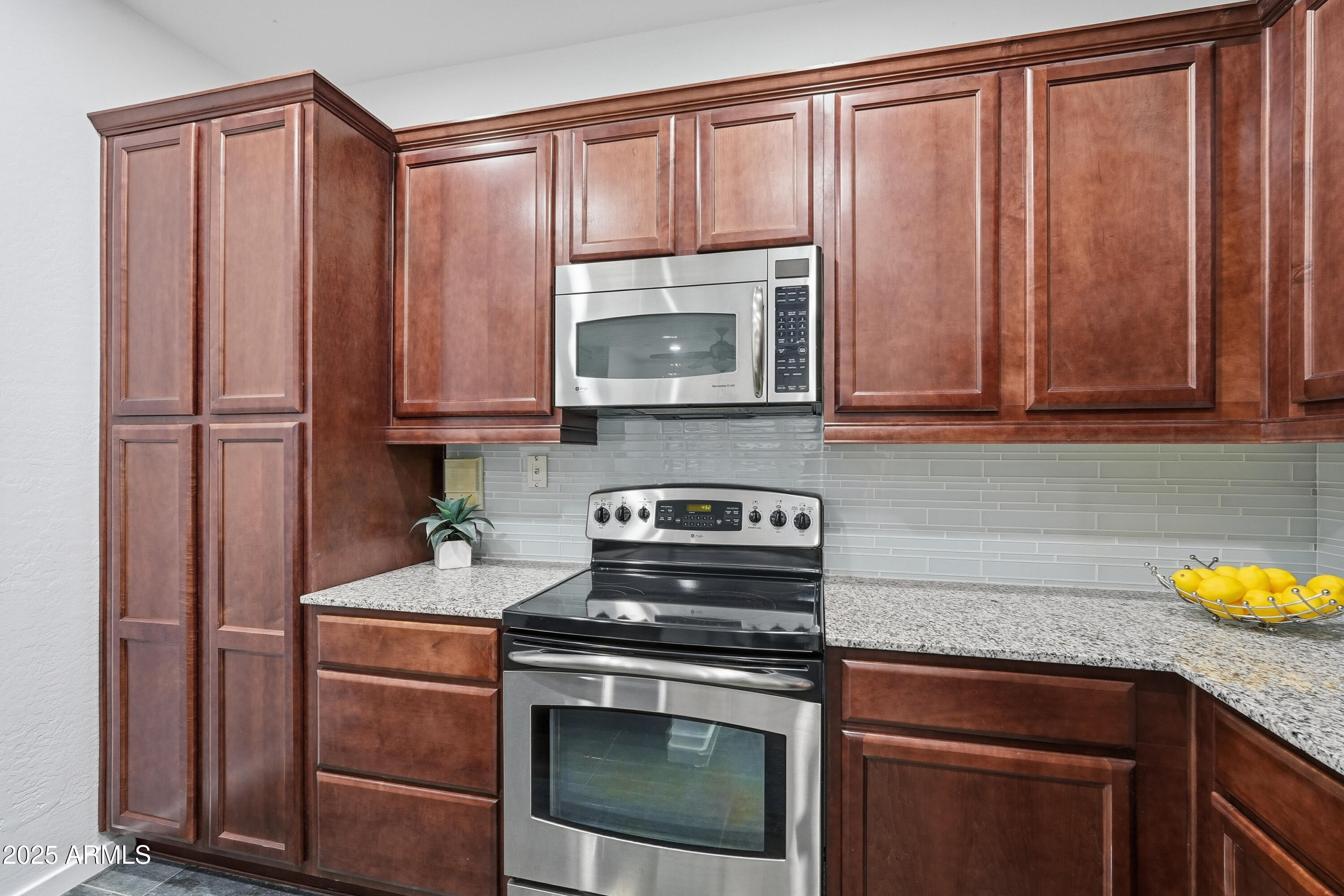 3935 East Rough Rider Road, Unit 1140 Phoenix, AZ 85050 - Photo 5 of 24 a kitchen with granite countertop wooden cabinets stainless steel appliances and a sink