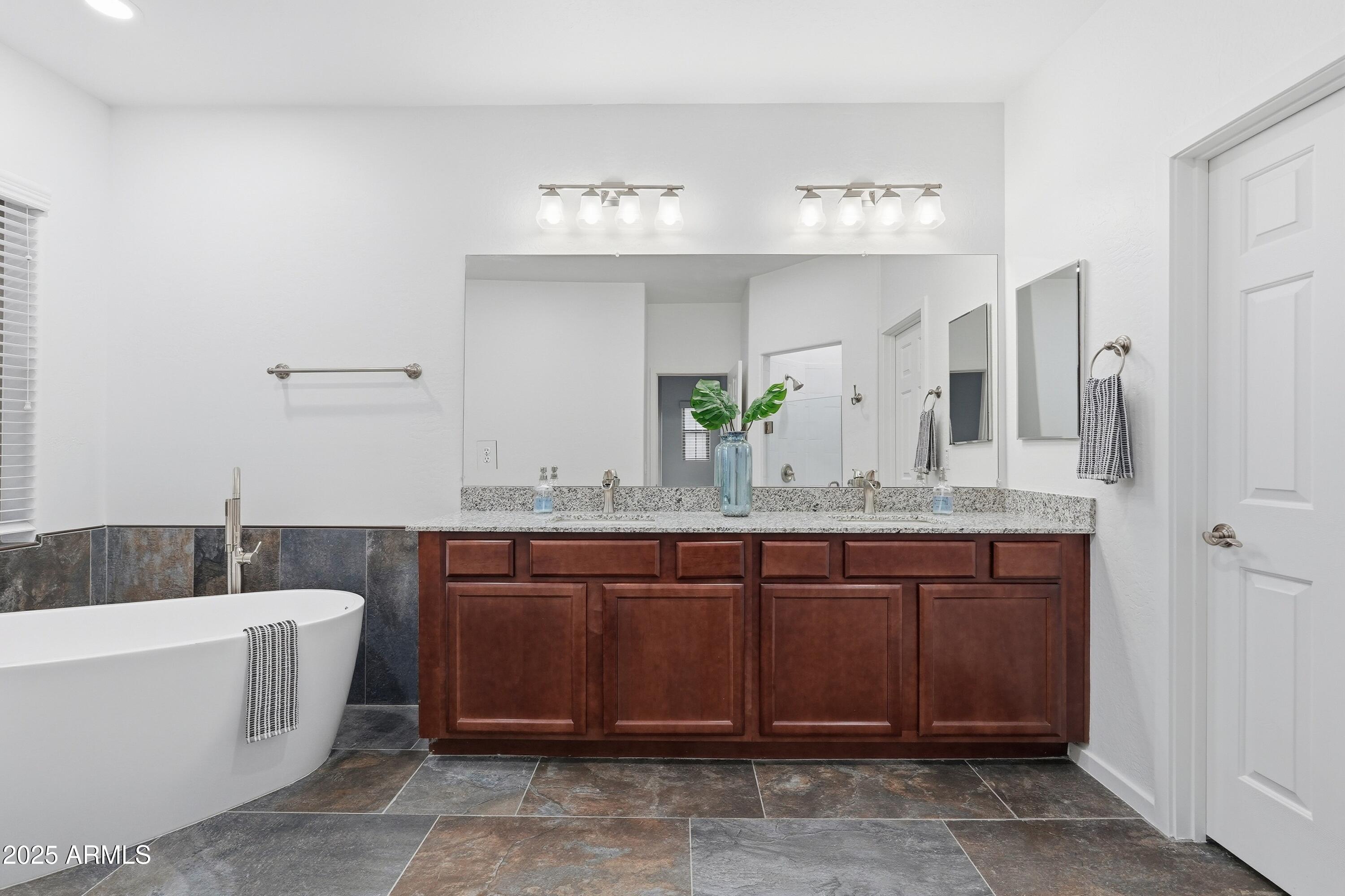 3935 East Rough Rider Road, Unit 1140 Phoenix, AZ 85050 - Photo 7 of 24 a bathroom with a granite countertop bathtub sink and mirror
