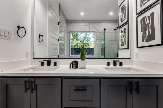 a bathroom with double vanity sinks a large mirror and a shower