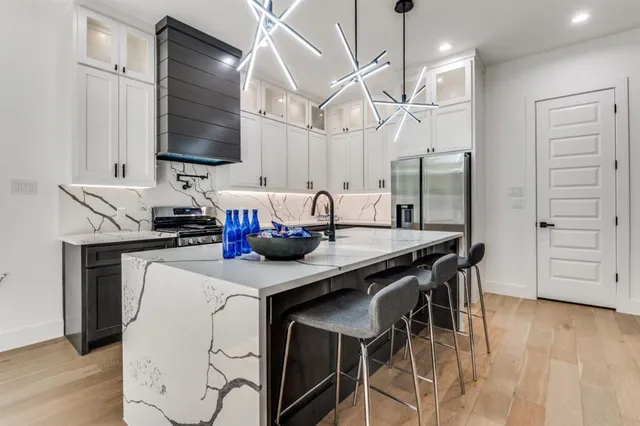 a kitchen with stainless steel appliances kitchen island granite countertop a table chairs in it and wooden floors