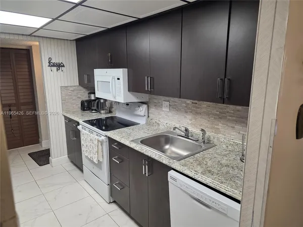 a kitchen with granite countertop a sink stove and cabinets