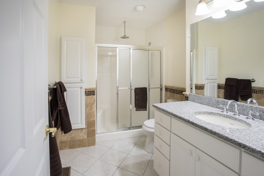 64 Gold Leaf Lane, Unit 64 Mashpee, MA 02649 - Photo 15 of 28 a bathroom with a granite countertop sink a mirror and a shower