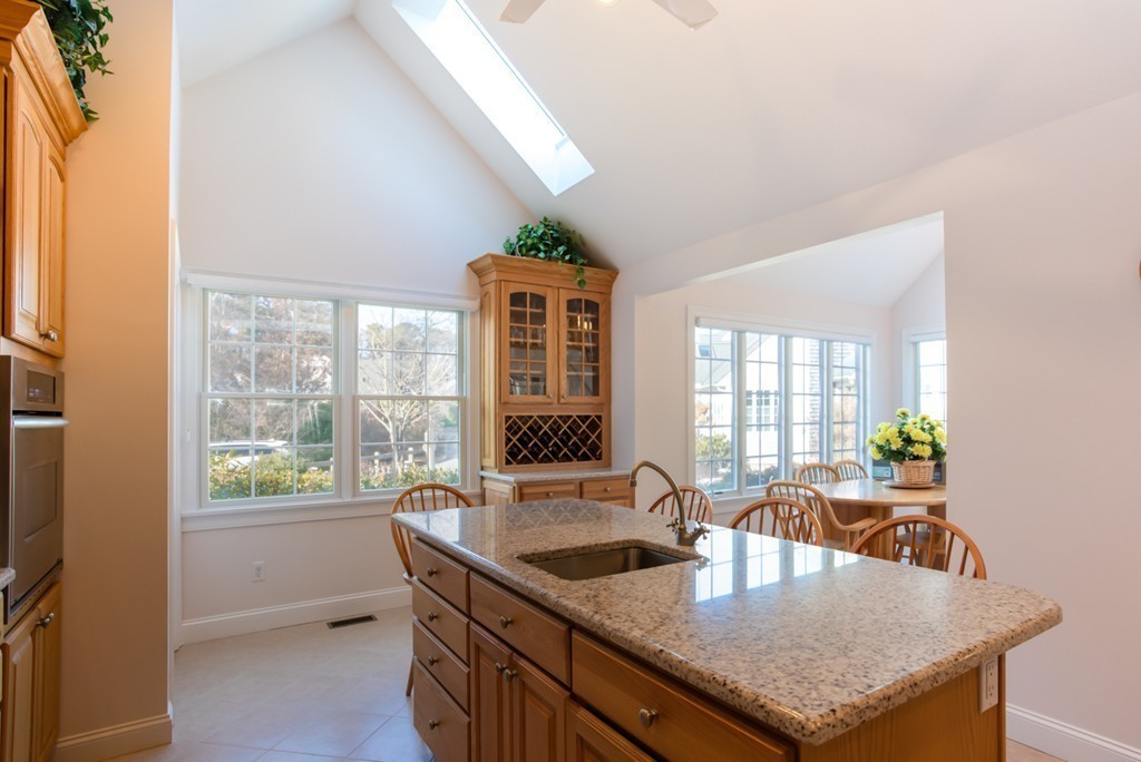 64 Gold Leaf Lane, Unit 64 Mashpee, MA 02649 - Photo 9 of 28 a kitchen with granite countertop a stove a sink a dining table and chairs