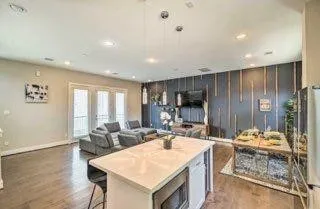 a living room with stainless steel appliances kitchen island granite countertop furniture a rug and a large window