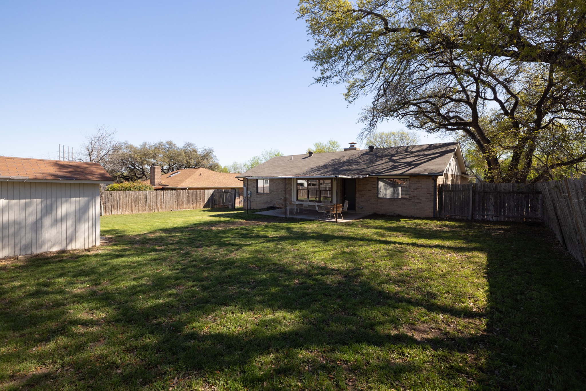 1101 Huntridge Drive Austin, TX 78758 - Photo 29 of 30 Back of house with a patio, a chimney, a fenced backyard, and brick siding