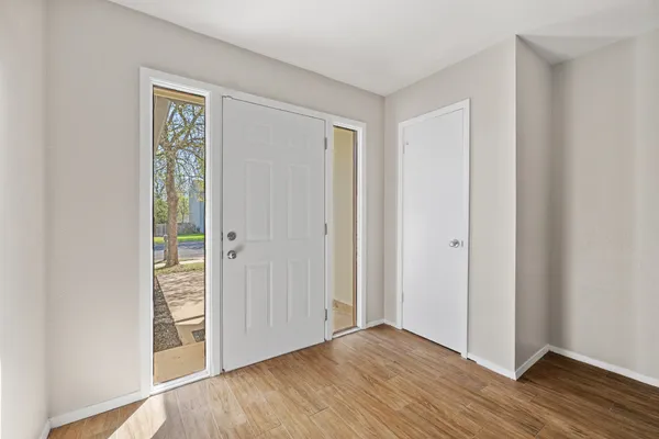 a view of an empty room with wooden floor and fireplace