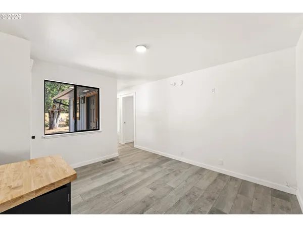 a view of an empty room with window and wooden floor