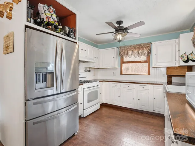 a kitchen with stainless steel appliances granite countertop a refrigerator stove and white cabinets