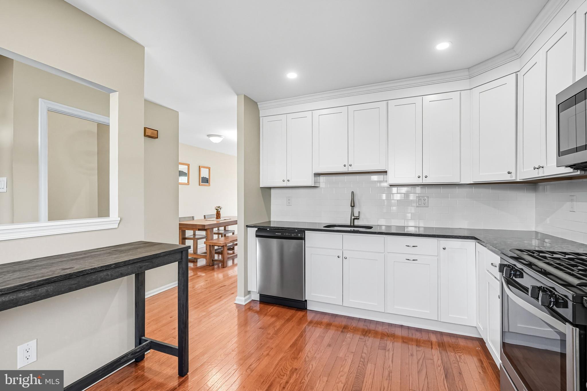 303 Scola Road Brookhaven, PA 19015 - Photo 11 of 56 a kitchen with stainless steel appliances granite countertop a stove a sink and white cabinets
