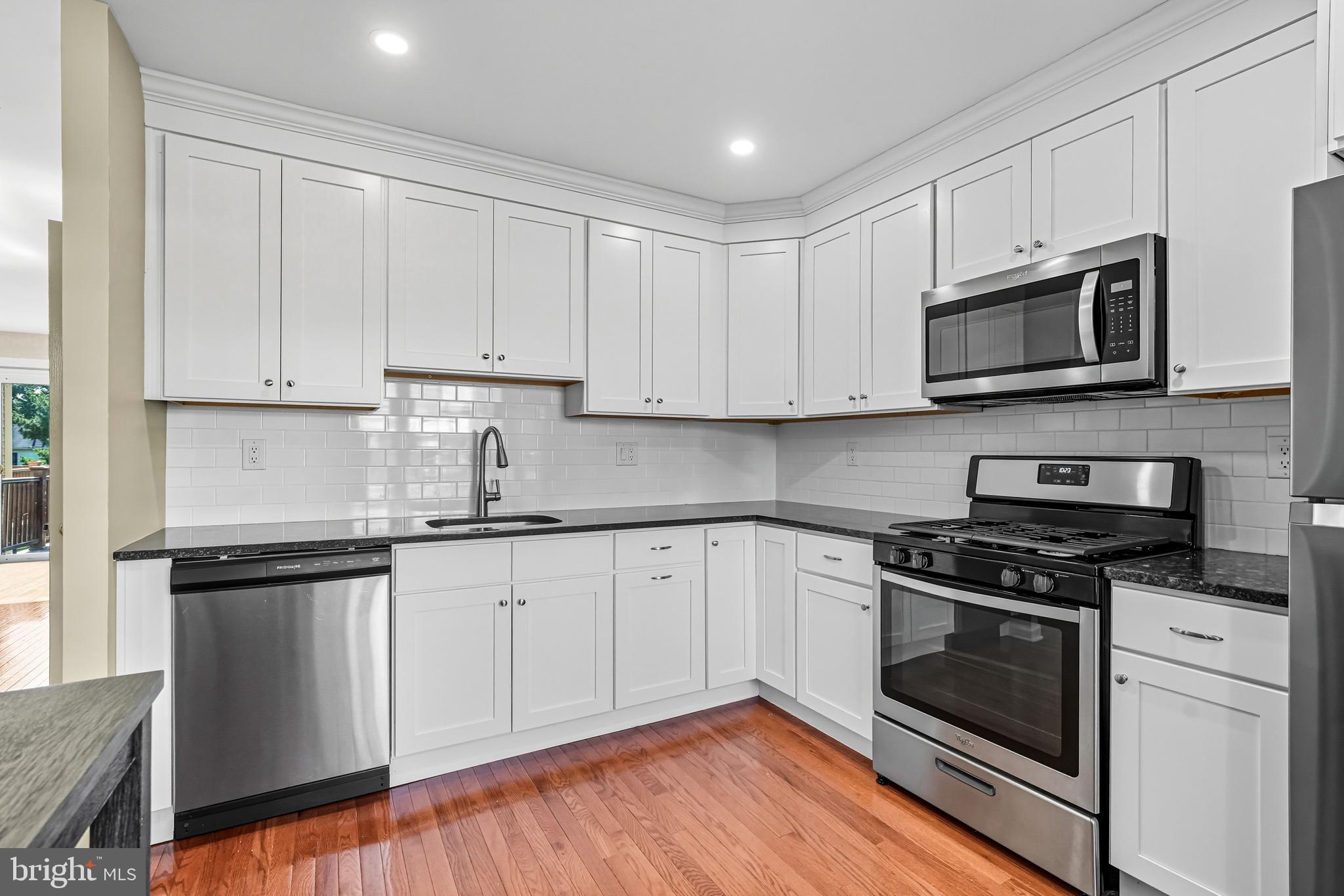 303 Scola Road Brookhaven, PA 19015 - Photo 9 of 56 a kitchen with granite countertop cabinets stainless steel appliances and wooden floor