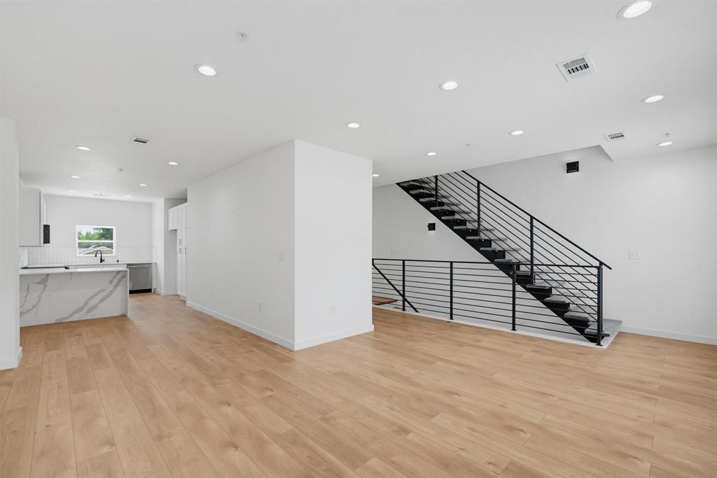 504 South O Connor Road Irving, TX 75060 - Photo 2 of 23 Open-concept living space featuring light wood-finish flooring, recessed lighting, and a contemporary staircase with black metal railings