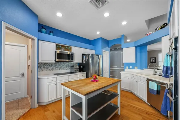 a kitchen with stainless steel appliances kitchen island granite countertop a stove refrigerator and cabinets