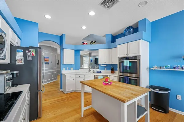 a kitchen with a refrigerator a stove top oven a sink dishwasher and wooden cabinets with wooden floor