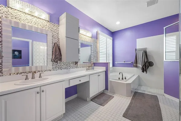 a spacious bathroom with a double vanity sink a large mirror and bathtub