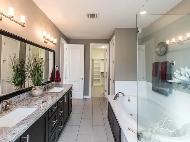 a spacious bathroom with a granite countertop sink mirror and bathtub