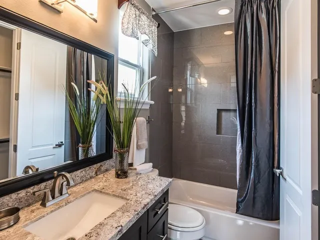 a bathroom with a granite countertop sink toilet and shower
