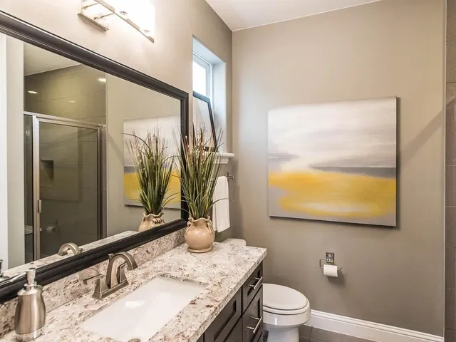 a bathroom with a granite countertop sink a toilet and mirror