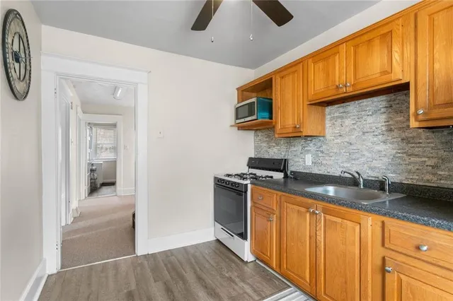 a kitchen with stainless steel appliances granite countertop a sink a stove cabinets and entryway