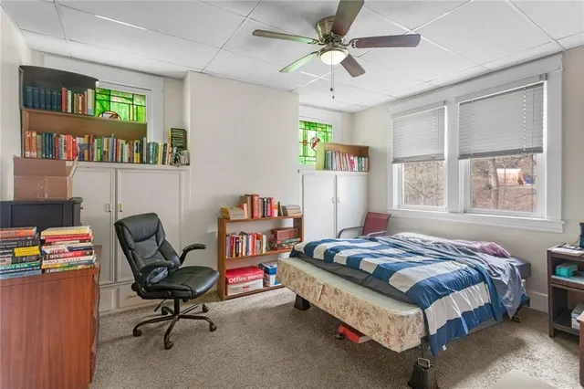 a bedroom with a bed a computer on the desk and a book shelf