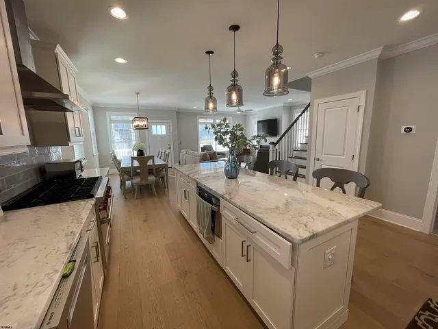 a kitchen with sink stove and white cabinets with wooden floor