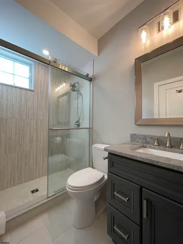 a bathroom with a shower sink vanity mirror and toilet