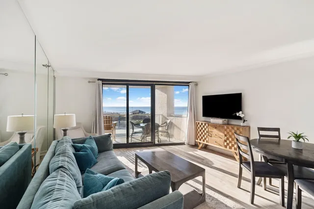 a kitchen with stainless steel appliances kitchen island granite countertop a refrigerator a stove top oven and a dining table with wooden floor