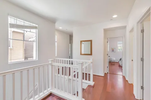 a view of hallway with wooden floor and windows