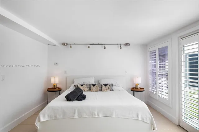 a white bed sitting in a room next to a window