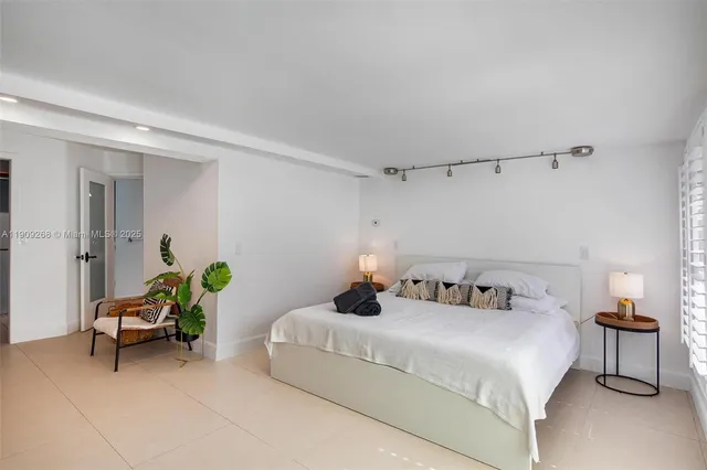 a bedroom with a bed mirror and window