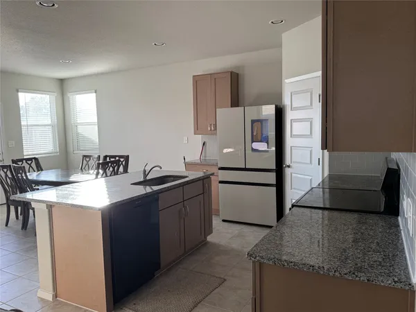 a kitchen with stainless steel appliances granite countertop a sink and a refrigerator