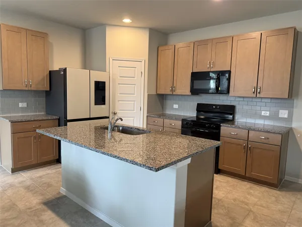 a kitchen with stainless steel appliances granite countertop a sink stove microwave and refrigerator
