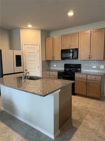 a kitchen with stainless steel appliances granite countertop a sink a stove a microwave a sink a refrigerator and cabinets