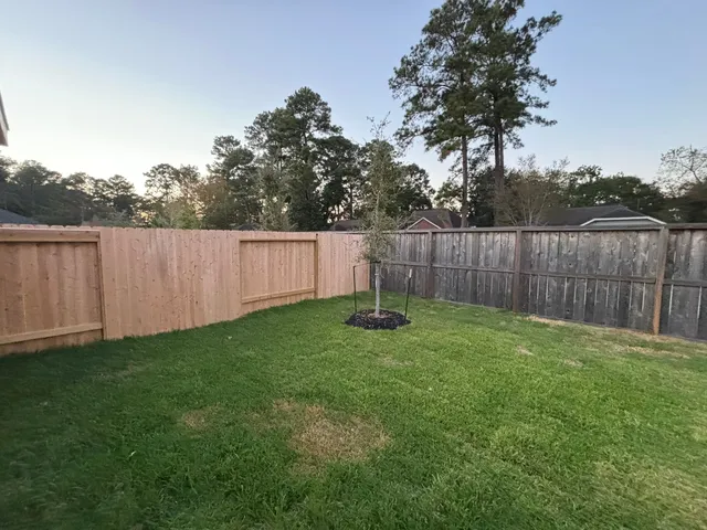 a view of a backyard with a garden and wooden fence