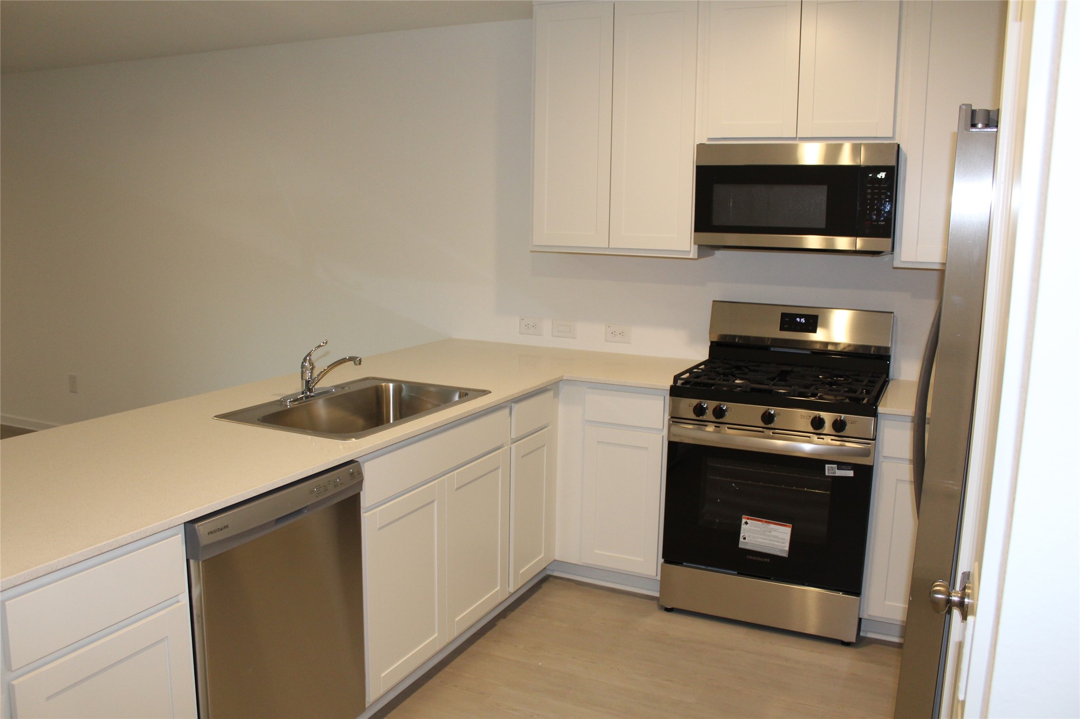 1733 Lofty Cedar Court Conroe, TX 77301 - Photo 4 of 18 a kitchen with a sink and a stove top oven with wooden floor