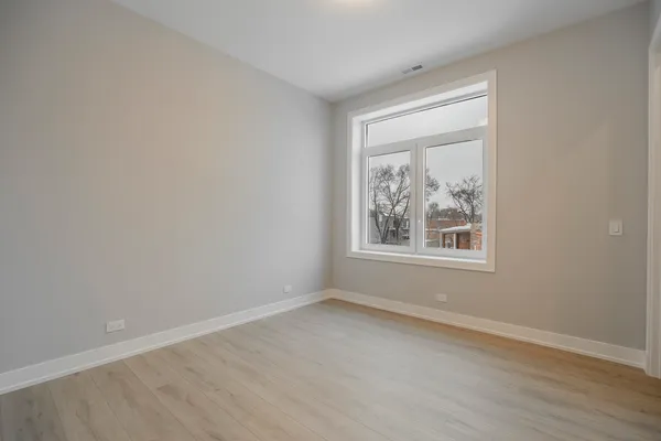 an empty room with a window and wooden floor