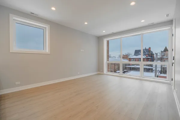 a view of a big room with wooden floor white walls and windows