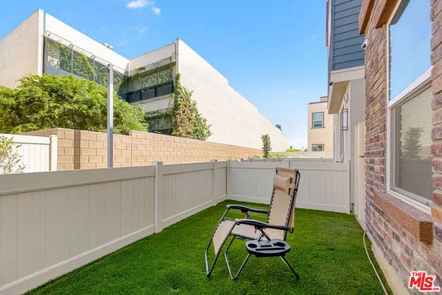 a view of a chair and table in backyard of the house