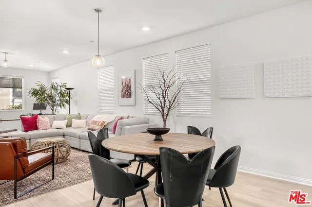 a kitchen with stainless steel appliances a sink a stove a refrigerator cabinets and a dining table