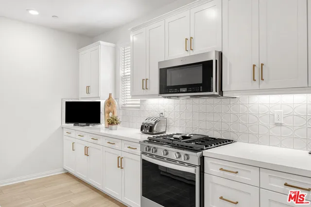 a kitchen with stainless steel appliances a dining table chairs microwave and sink
