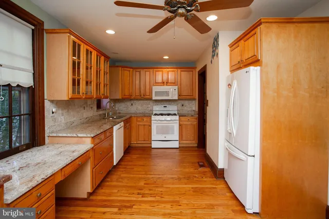 a large kitchen with stainless steel appliances granite countertop a refrigerator a sink dishwasher a stove and a dining table with wooden floor