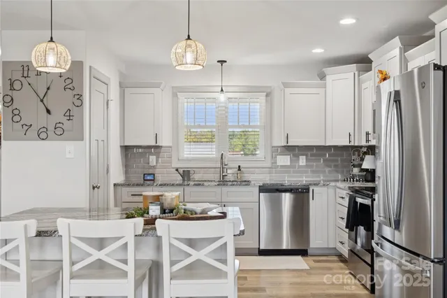 a kitchen with stainless steel appliances granite countertop a stove top oven a refrigerator a sink and dishwasher a oven with wooden floor