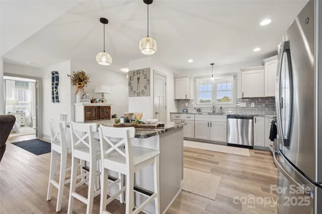 a kitchen with stainless steel appliances granite countertop a sink a stove a refrigerator and island with wooden floor