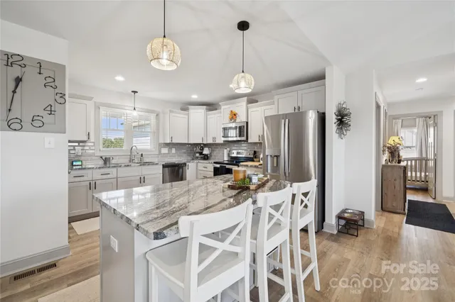 a kitchen with granite countertop a refrigerator a stove a sink dishwasher a dining table and chairs with wooden floor