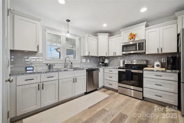 a kitchen with stainless steel appliances granite countertop a stove a sink and a microwave