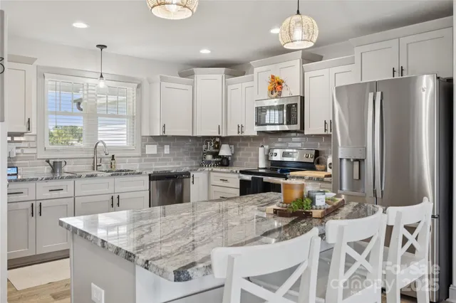 a kitchen with stainless steel appliances granite countertop a stove refrigerator sink and microwave