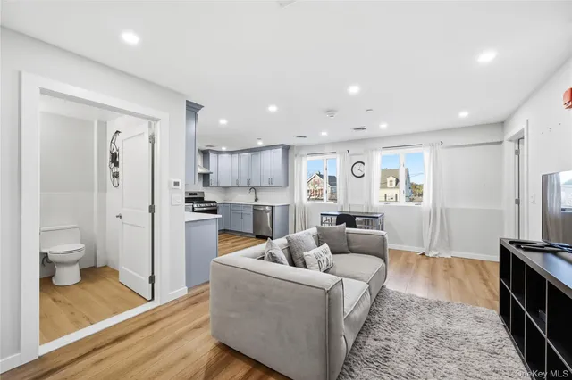 a living room with furniture and a large mirror next to a window